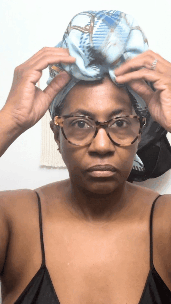 Image of a woman putting on a satin scarf as part of her nighttime hair care routine