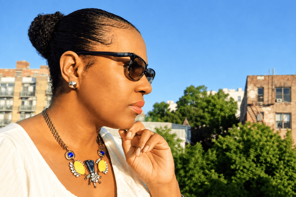 side shot of a black woman with a sleek hair bun standing outdoors
