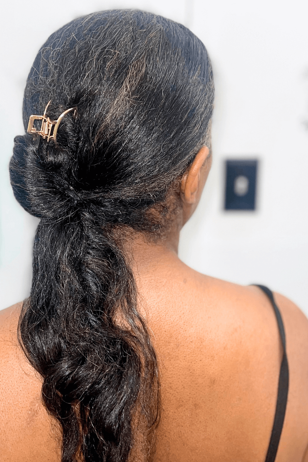 black woman with straightened natural hair in a half up bun half down ponytail