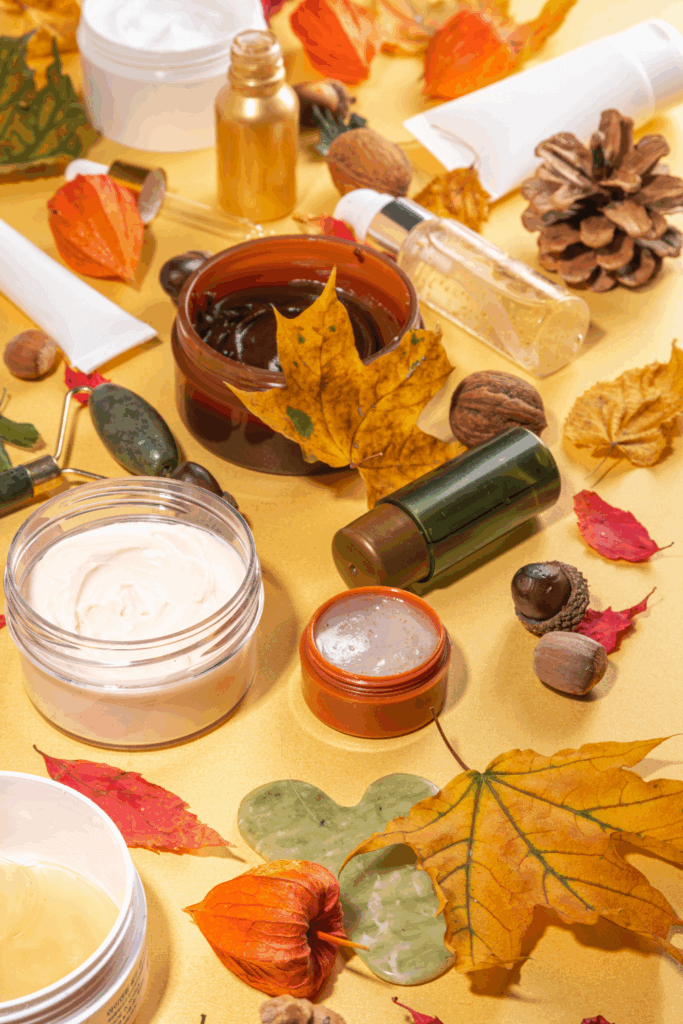 Fall-themed flat lay featuring hair creams, oils, serum bottles, and natural elements like pinecones, acorns, and autumn leaves.