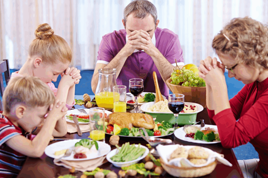 white family with heads bowed praying over thanksgiving dinner
