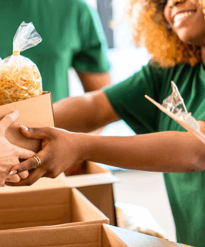 a smiling woman giving a box of food to someone