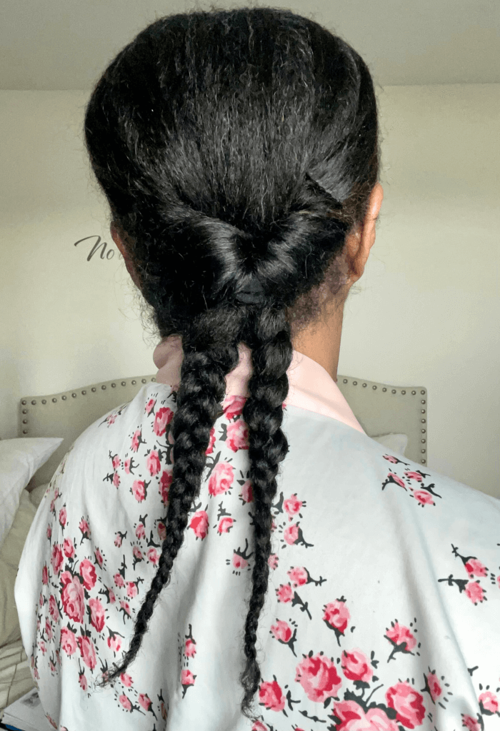 Back view of a looped braided ponytail on long natural hair, gathered low with two thick braids hanging down