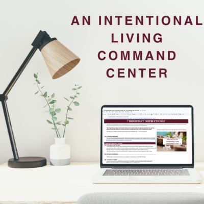 Lifestyle mockup of the Intentional Living command center open on a laptop beside a desk lamp and plant.