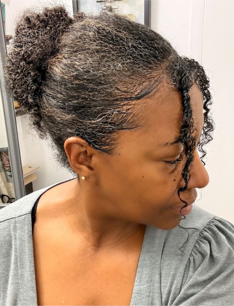 Natural hair bun with defined curly tendrils framing the face for a fall protective style