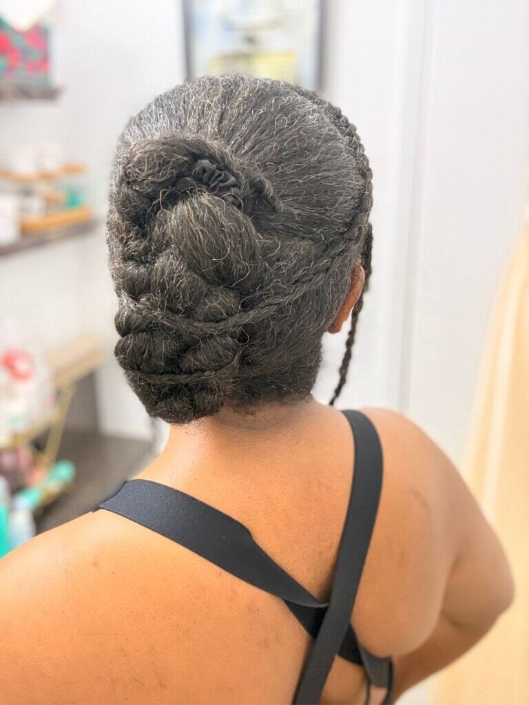 Back view of elegant braided natural hairstyle with hair tucked into a low updo