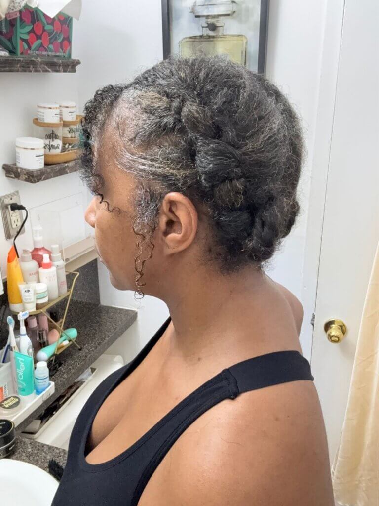 Side view of natural hair updo with connected braids and curly face-framing tendrils