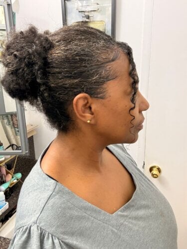 Side view of protective natural hair bun with curly tendril in front